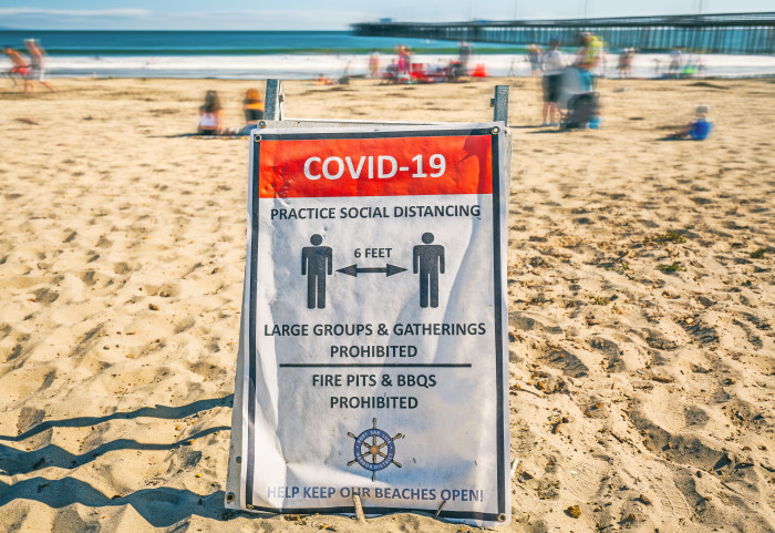Sign on a beach warning of COVID-19