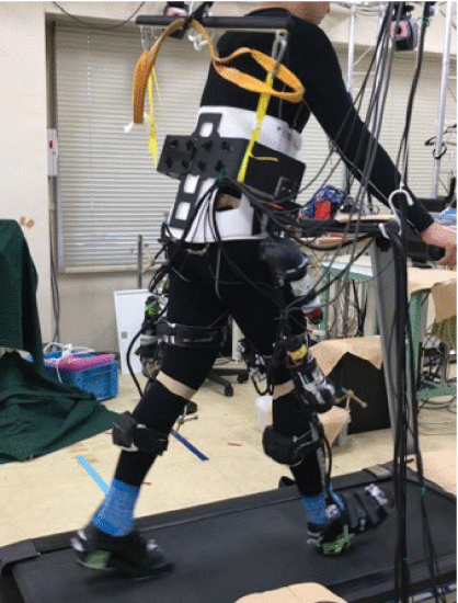 Fig. 6. - Experimental setup showing a subject walking on a treadmill with the lower limb exoskeleton.