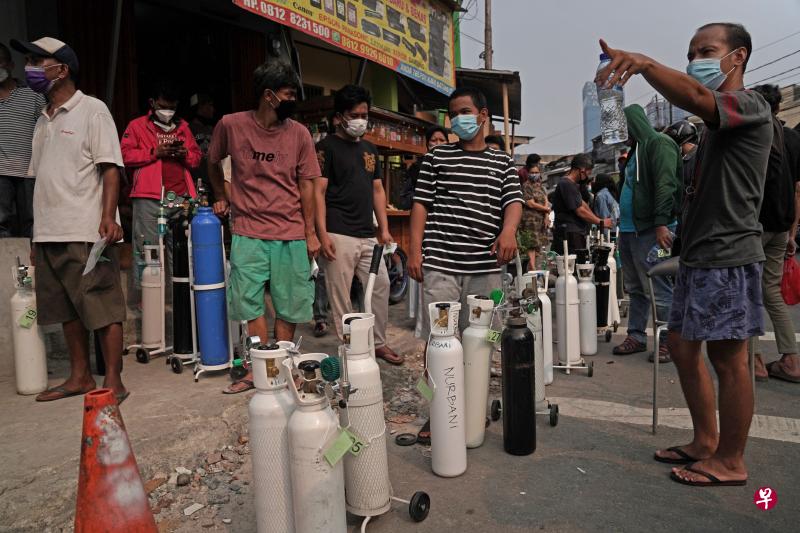 由于雅加达面临医用氧气供应短缺问题，当地居民昨天纷纷带着氧气筒到城里的商店外排队添购氧气。（彭博社）